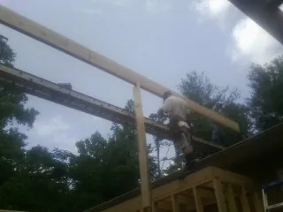 Carpenter setting a ridge beam over a new addition frame — Ice Dam Removal by Roofing Brothers in Adrian