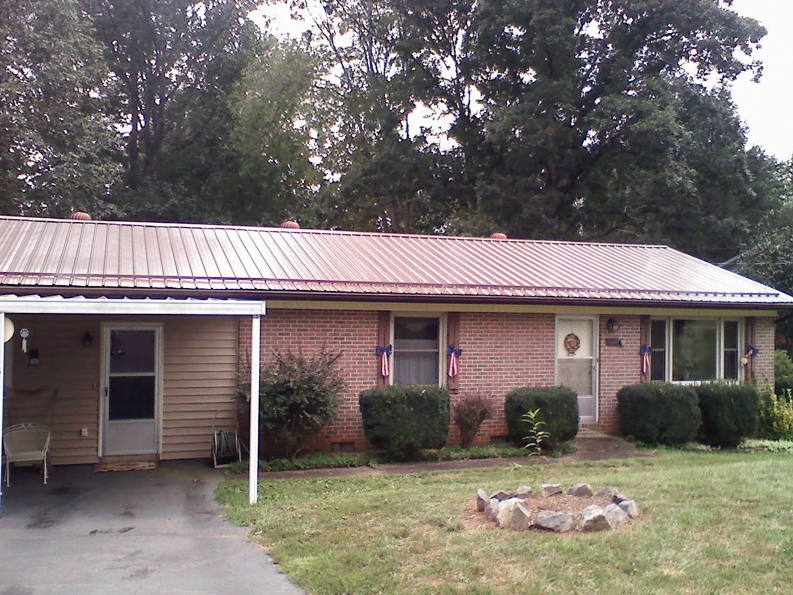 Bronze metal roof and carport on a brick ranch home — Roof Repair work by our crew in Adrian